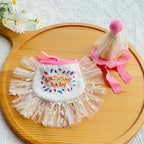 Flat-lay of pink birthday bib and matching tulle party hat