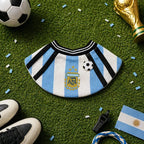 Flat-lay of the blue and white soccer-inspired pet bib with football charm on grass