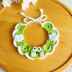 Flat-lay of artisan green frog knit pet collar on wooden tray