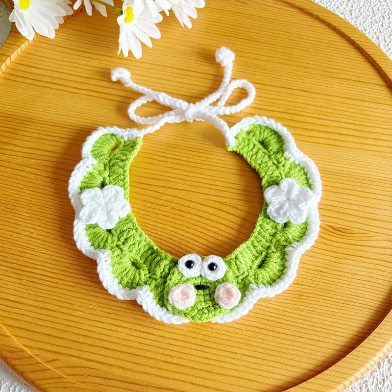 Flat-lay of artisan green frog knit pet collar on wooden tray